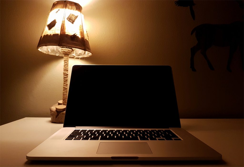 Laptop computer on table with lamp at home