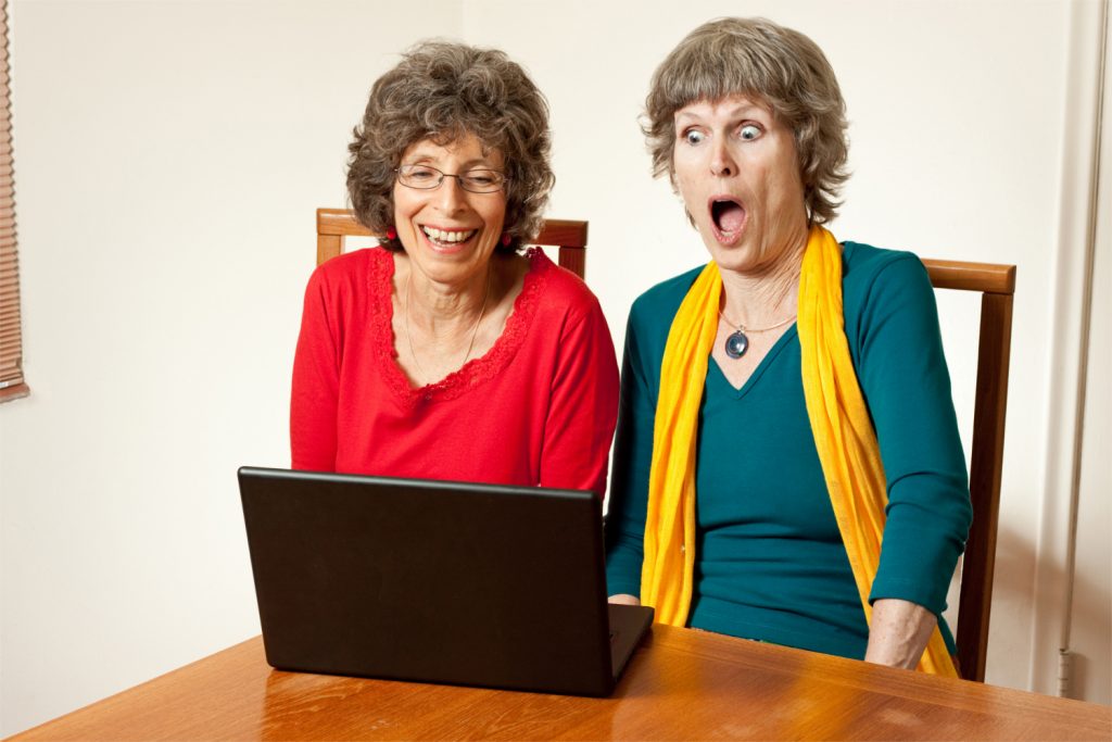 Two older ladies with laptop - one has shocked the other